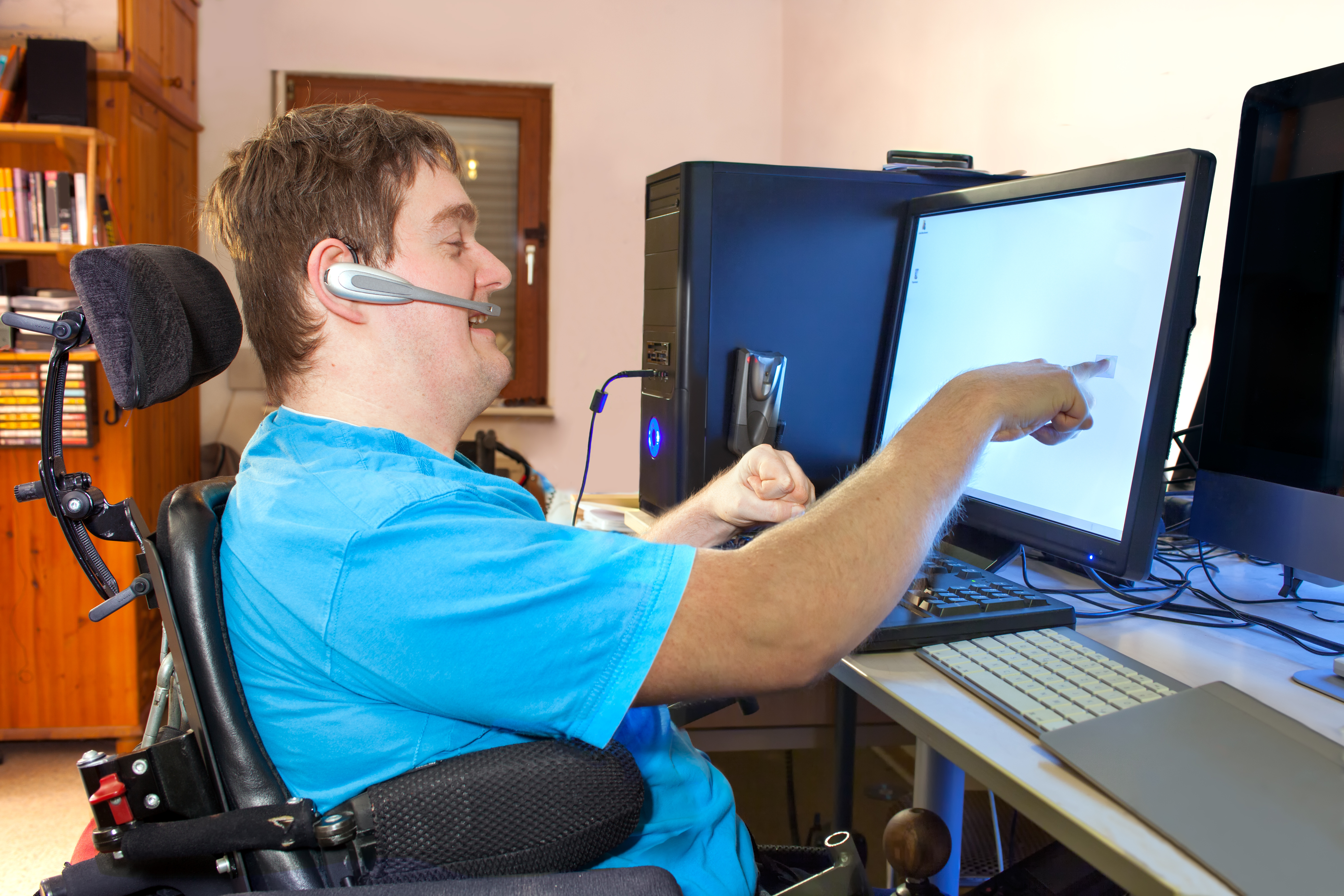 Image - a person with a disability; on a wheelchair; interacting with the computer in front of him.